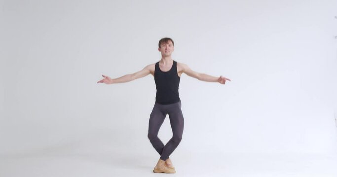 Young male, ballet dancer performs pirouette and acrobatic elements in ballet dance, white background.