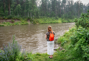 Woman admiring the flow of the river against the forest