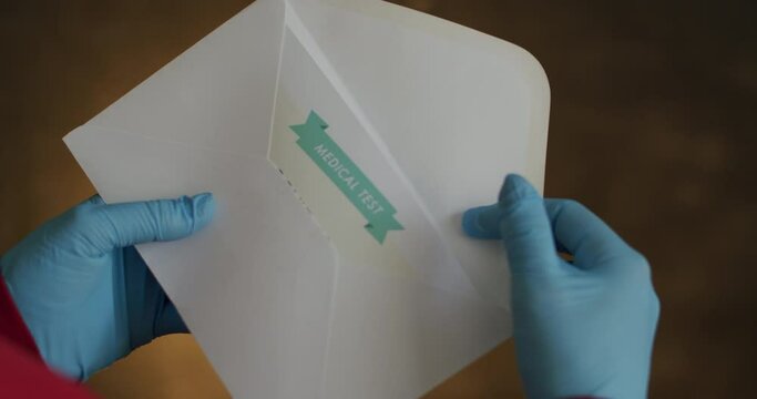 Person Opening Envelope with Certificate with Positive Results in Covid-19. Closeup of Person Wearing Surgical Gloves Slowly Opening Envelope and Pulling Out Positive Test Results in Coronavirus.