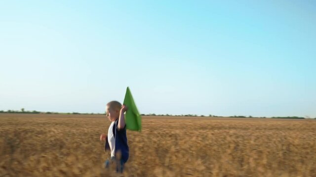 outdoors games, boy with down syndrome with emotions on his face plays with paper airplane in a wheat field on background of a blue sky