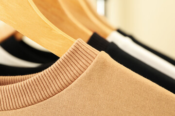 Hangers with stylish sweatshirts, close up and space for text