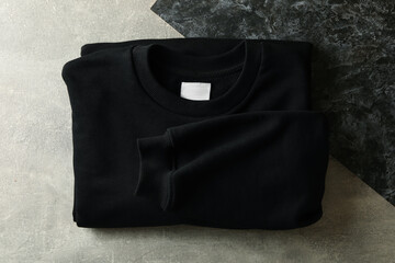 Black folded sweatshirt on two tone background