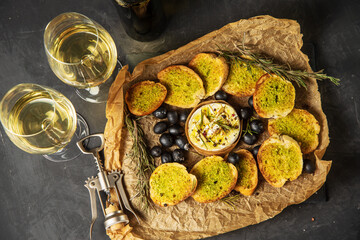 Table setting with snacks under a glass of white wine. Camembert cheese with baguette toast with...