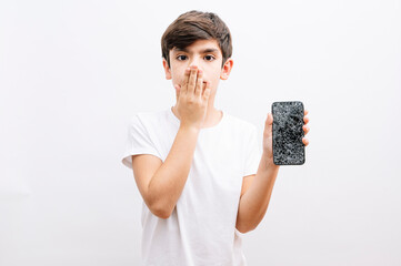 Dark haired little child holding broken smartphone cover mouth with hand shocked with shame for...