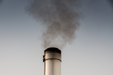 Smoking stainless steel chimney in front of morning sky
