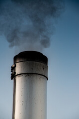 Smoking stainless steel chimney in front of morning sky