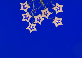 Garland with wooden stars on a blue background. Christmas, new year 2021. Flat lay, copy space, top...