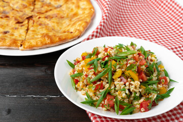 Georgian Tabbouleh salad with bulgur and vegetables on black wooden table