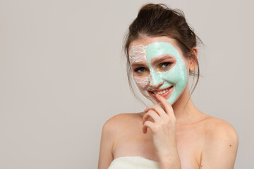 young woman with cream on her face. skin care. Gray background