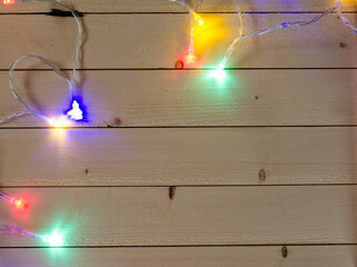 Wooden table with beads in the form of snowflakes and colored Christmas lights