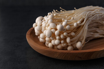 Enoki mushrooms over black background .Enokitake or enoki (Flammulina velutipes) white mushroom used i food and salads, also known by the name golden needle mushroom or lily mushroom.