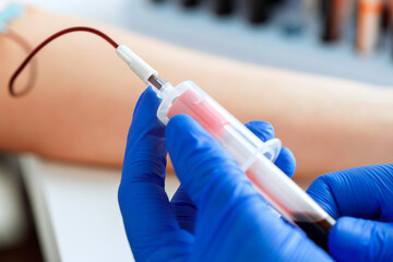 Hands of a doctor taking blood samples using a tube holder