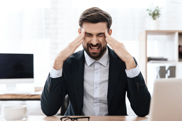Fototapeta premium A man in a suit sits and feels pain in his head.
