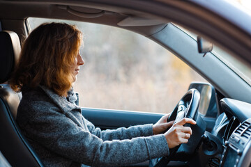 Portrait of a redhead woman driving a car and looking straight ahead.