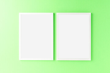 Two empty picture frames on green wall. Mockup with copyspace