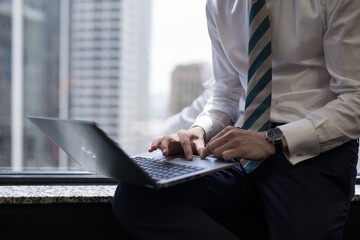 Male man office worker using his laptop computer in office with city skyline in the background