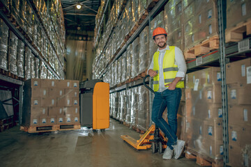 Young male worker standing near shelves and looking determined