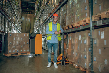 Fototapeta premium Young male worker standing near the loader and smiling