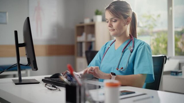 Hispanic Doctor's Office: Female Head Nurse Sitting at Her Desk Working on Personal Computer. Medical Health Care Specialist Filling Prescription Forms, Checking Analysis Test Results. Arc Shot