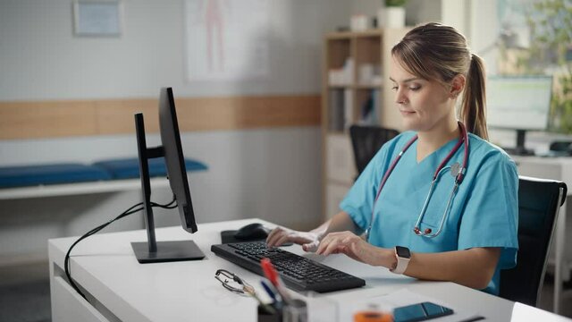 Hispanic Doctor's Office: Experienced Head Nurse Sitting at Her Desk Working on Personal Computer