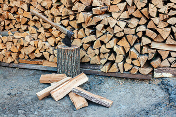 Old ax and a deck for chopping wood. Dry oak firewood stacked in a pile, chopped wood for winter...