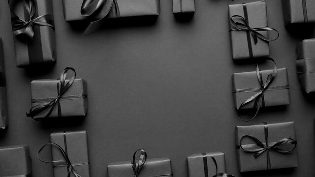 Arranged Gifts boxes wrapped in black paper with black ribbon on black background. Christmas concept