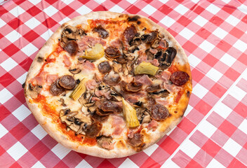 A fresh pizza under red and white tablecloth background