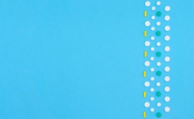 Multicolored pills, tablets and capsules of pharmaceutical medicine on a blue background. Copy space, flat lay, top view