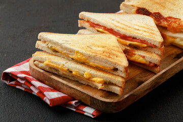 Sandwiches cut into halves on wooden cutting board with napkin