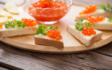 toast with red caviar on  wooden tray