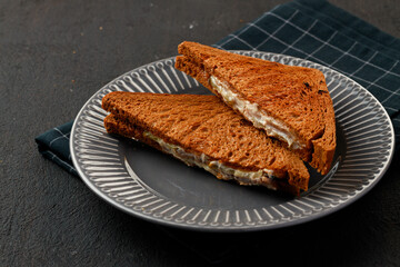 Toasted rye sandwich with ham cut into halves on table
