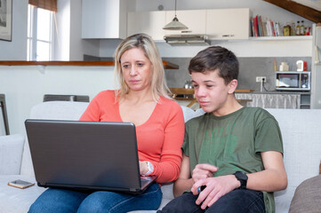 Adolescent et sa mère assis ensemble devant l'écran d'un ordinateur portable