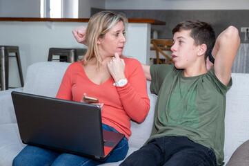 Adolescent et sa mère assis ensemble devant l'écran d'un ordinateur portable