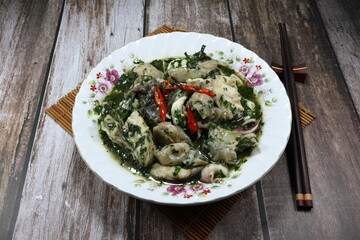 Fried and stirred mixed fish fillet, fresh squid and fish ball seasoning with spicy basil sauce on the plate. Famous traditional appetizer menu in Asia seafood restaurant. 