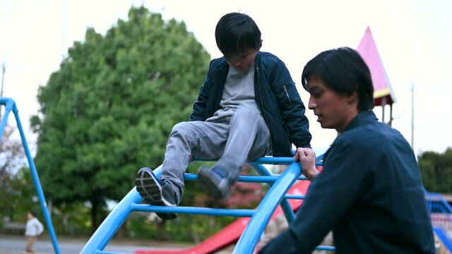 公園で遊ぶ男の子の世話をする若い男性