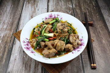 Fried and stirred spicy chicken meat with spring onion, chilly and seasoning with soy sauce and pepper on the plate. Famous traditional appetizer menu in Asia restaurant. 