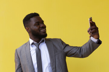 Happy young african american guy in casual t-shirt posing isolated on yellow orange background.