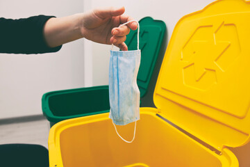 The woman throwing the medical mask into one of three trash bins