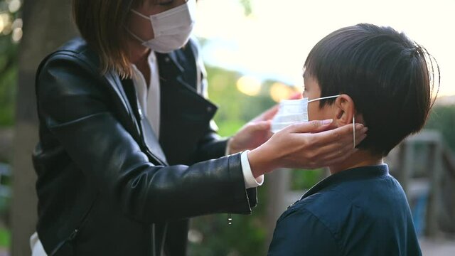 小学生の息子マスクをつける母。covid-19対策。