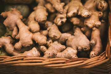 There are many ginger roots in a large square wicker basket. Harvest vegetables in the grocery store.