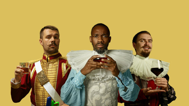 Medieval men as a royalty persons in vintage clothing drinking alcohol, wine and whiskey on yellow background. Concept of comparison of eras, modernity and renaissance, baroque style. Creative collage