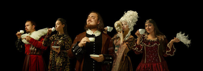 Medieval people as a royalty persons in vintage clothing drinking coffee, tea on dark background....