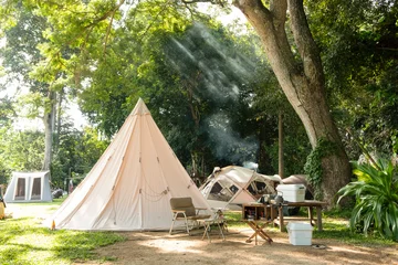 Fotobehang A large white traditional teepee tent with luxurious glamping interiorwith desk and chairs in forest,holiday/vacation,Camping © Nipapun