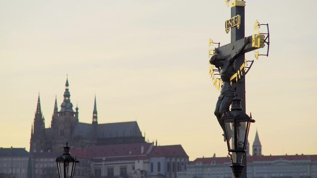  Dusk shot silhouette of a crucifix and statues decorate Charles bridge against Prague castle 