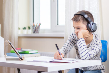 Online learning, remote education at home. Kid with digital tablet computer having online leasson, making homework