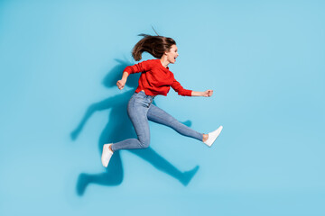 Fototapeta na wymiar Full length profile photo of funky lady jump high up running wear red sweater sneakers jeans isolated blue color background