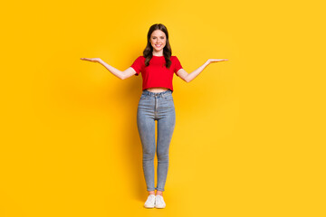 Full length photo of attractive lady hold two open palms wear cropped top jeans footwear isolated yellow color background
