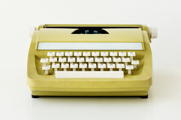 Retro pastel yellow typewriter on off white background