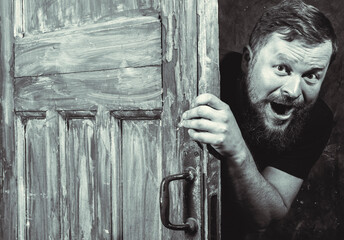Cheerful bearded man peering out of the door