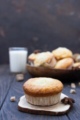 Vanilla cinnamon crumble muffins with coconut filling, spices and glass of milk on wooden table. Rustic background.
